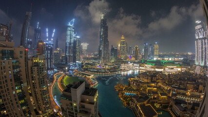 Skyscrapers rising above Dubai downtown night timelapse surrounded by modern buildings aerial top view