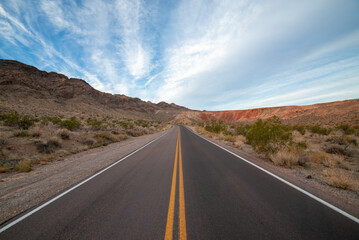 Fototapeta na wymiar Driving down an empty road through the desert mountains