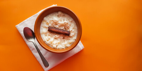 Mungunzá with cinnamon in brown porcelain pot and orange background with space for text 