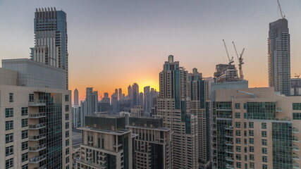 Obraz na płótnie Canvas Dubai skyscrapers with golden sky over business bay district day to night timelapse.