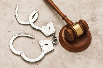 Open handcuffs and a judge gavel on the table, concept on the topic of release by court order