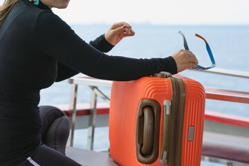 The orange luggage of Asian woman relaxing on balcony enjoying view from boat of Samui island in...