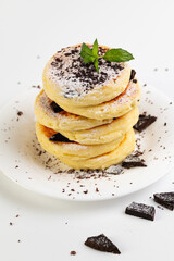 curd cakes, curds on a white dessert plate with chocolate and mint on a white plate, vertical format