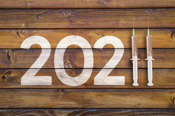 happy new year 2022. year 2022 with two vaccines on wooden desk
