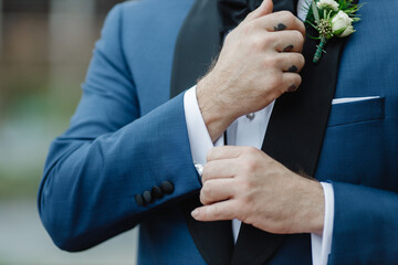 A man in a blue suit straightens his sleeves Close up A man buttoning a blue jacket male hands...