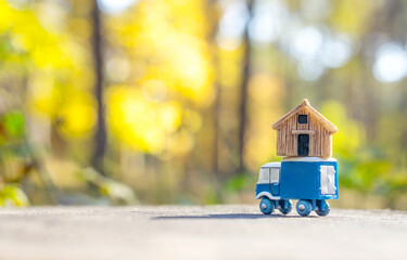 Toy truck carrying a tiny house against a forest background
