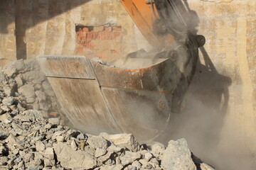 Aufladen von Bauschutt mit einem Bagger in staubiger Umgebung