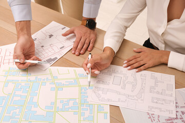 Professional cartographers working with cadastral map at table, closeup
