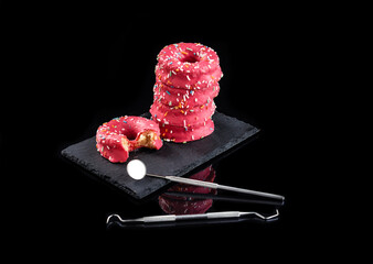 torre de donuts encima de un plato de pizarra sobre fondo negro e instrumental de dentista