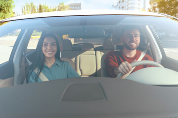 Young woman and driver in modern car, view through windshield