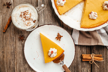 Fototapeta premium Traditional autumn dish Spicy pumpkin pie with whipped cream latte with cinnamon on black stone table. Healthy food trend. top view