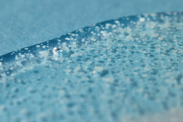 Texture of transparent gel with polishing beads on blue.