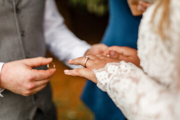 Obraz premium Newlyweds exchange rings groom puts the ring on the brides hand The moment of the exchange of the rings The groom puts a wedding ring on the bride in white dress finger Wedding details 