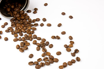 Roasted coffee beans on a white background. Overturned coffee can, coffee beans scattered on the table