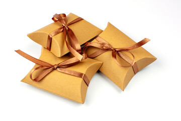 Small gifts in a box made of natural cardboard. The craft box is tied with a brown satin ribbon. Group of gifts, copy space. Gift boxes with recycled paper on white.