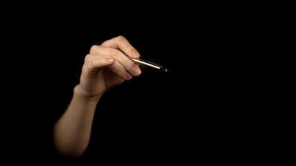 Hand holding silver pen isolated on a black background. Signature concept, blank empty copy space photo