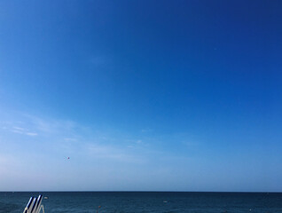 An empty blue and white chaise longue on the horizon. Background of the sea. Minimalism, Summer...