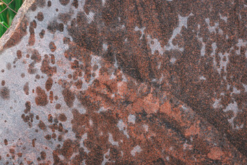 Red granite texture. A variegated, spotted background of red (brown) granite. The stone granite surface of brown-gray color. Surface view of granular igneous rock