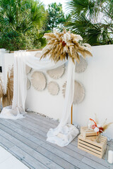 White wooden square arch Wedding decoration on open-air aerial white cloth background view of trees and palms outdoor wedding concept Arch decorated with dried flowers 
