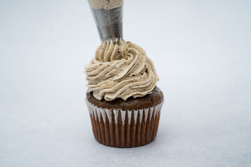 black cupcake decorated with a piping bag white cream