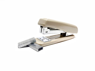 Staples piled on white paper background next to a big stapler