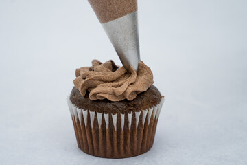 black cupcake decorated with a piping bag chocolate cream