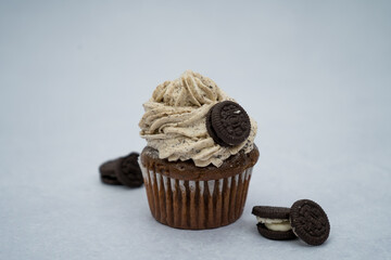 black cupcake decorated with a piping bag white cream with cookies