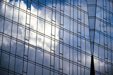 blue sky and clouds reflected from a a glass skyscraper with geometric shapes