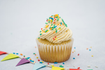 Vanilla cupcake decorated with piping bag and sprinkles