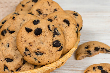 Chocolate chip cookies in a basket on a white wooden table. Close-up.