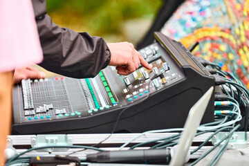 Sound engineer hand adjusting audio mixer at live concert, stage sound mixer, audio mix slider