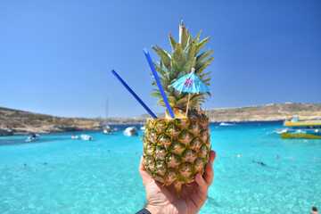 Pineapplecocktail drink over Blue Lagoon on Comino island, Malta.