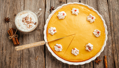 Homemade pumpkin cheesecake with coffee on wooden background, banner, menu, recipe place for text, top view