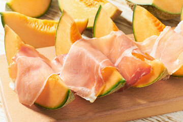 Italian prosciutto ham with melon. Slices of traditional ham wrapped around cantaloupe melons.
