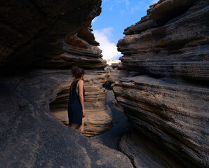 woman looks at the sky between the cracks of a rock