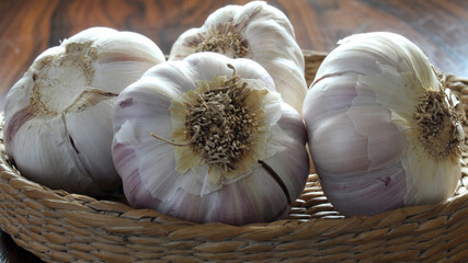 Garlic basket. Garlic bulbs close up in basket on wooden table