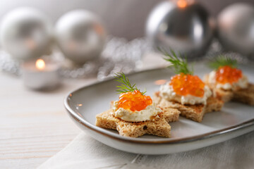 Holiday canapes with red caviar, cream and dill garnish on toasted bread in star shape on a gray...