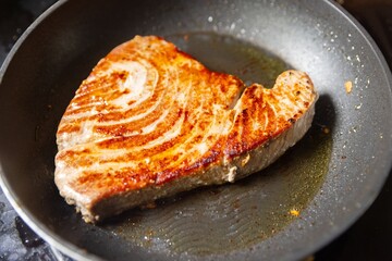 Salmon steak in frying pen closeup photo