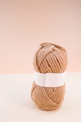 Vertical shot of isolated soft beige yarn ball on an a coral background