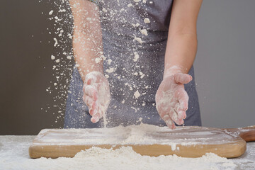 Chef in the kitchen, hands pouring the flour for making dough. Clap hands, a cloud of flour. Shallow depth of field