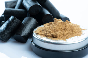 Closeup of salmiac powder and a bunch of Finnish black licorice against a bright white background