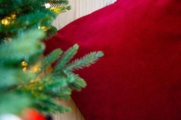 New Year and Christmas background. Red pillow on a background of blurry fir branches. Place for text or product, copy space