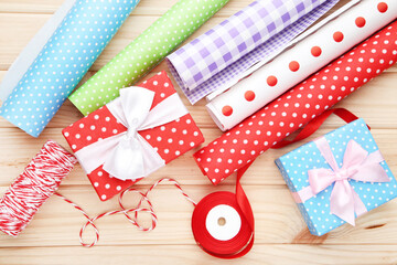 Obraz premium Rolls of craft papers with gift boxes, ribbon and rope on wooden background