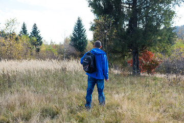 Naklejka na ściany i meble Man with a backpack stay in autumn forest 