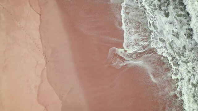 Waves of the sea from above in 4K. Aerial view of a coastal city with sandy beaches and holiday homes in Portugal. Praia de Quiaios, Portugal - sandy beach popular for surfing, bodyboarding.