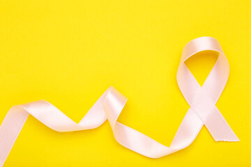 Cancer concept. Pink ribbon on yellow background