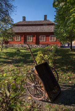 Old falu red bulding and an old pushcart in a park a colorful autumn day in Stockholm,