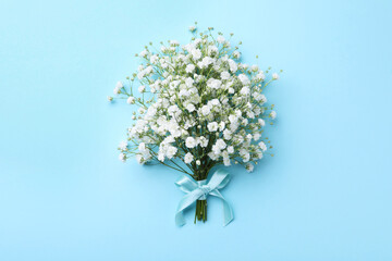 Beautiful gypsophila flowers tied with ribbon on light blue background, top view