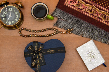gift box, rosary, with quran islamic book, prayer beads and Muslim prayer rug on wooden background