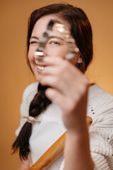 Fototapeta premium Woman happily looks through a metal shape in the form of a Christmas tree for baking. Confectionery concept.